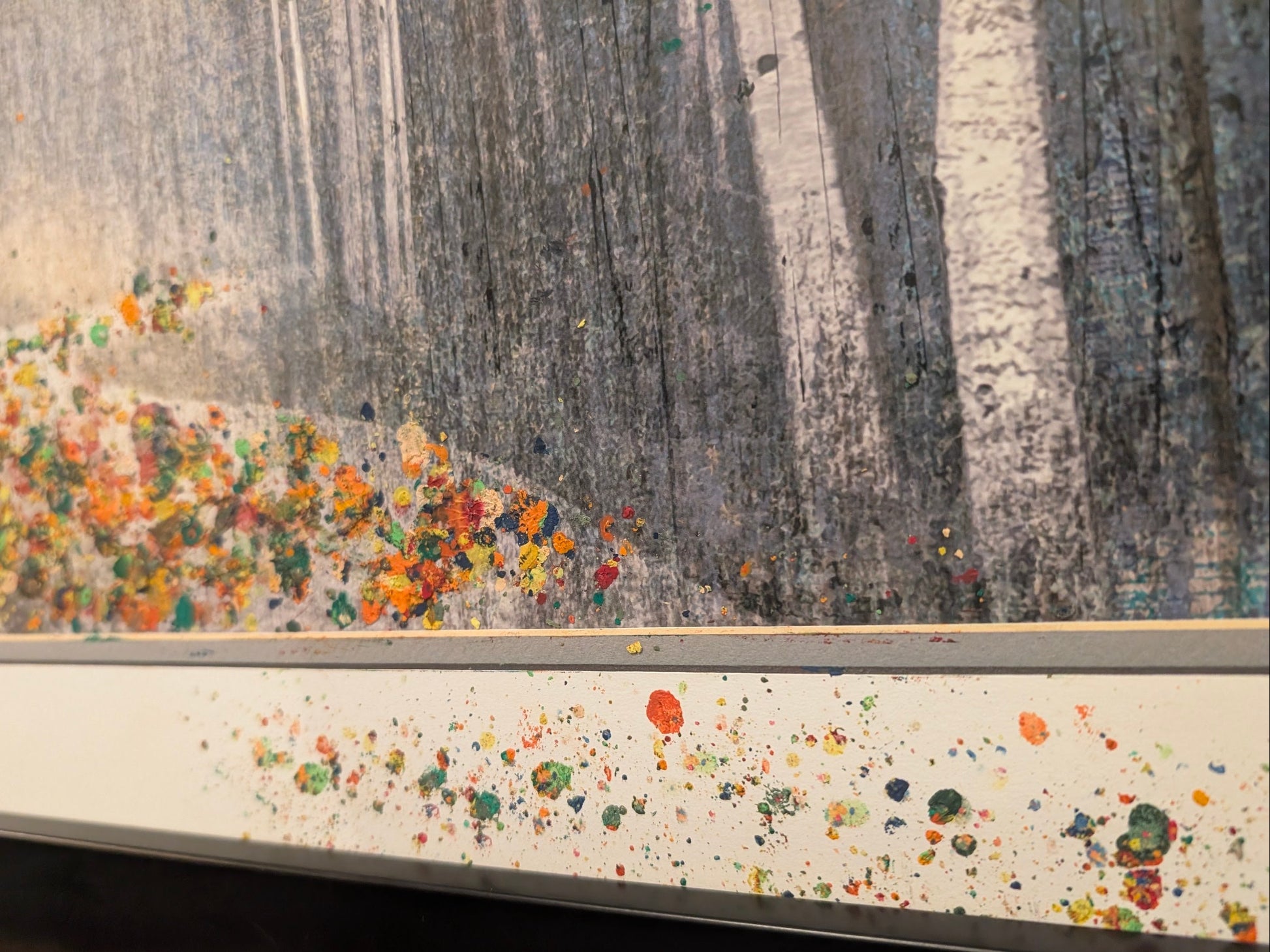 Close-up of a textured surface with colorful specks and a blurred natural scene.